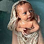 baby, child, infant, towel, water, bath, skin, hands, face, blue_eyes, wet_hair, expression, curious, holding, arm, human, newborn, soft_fabric, closeup, portrait