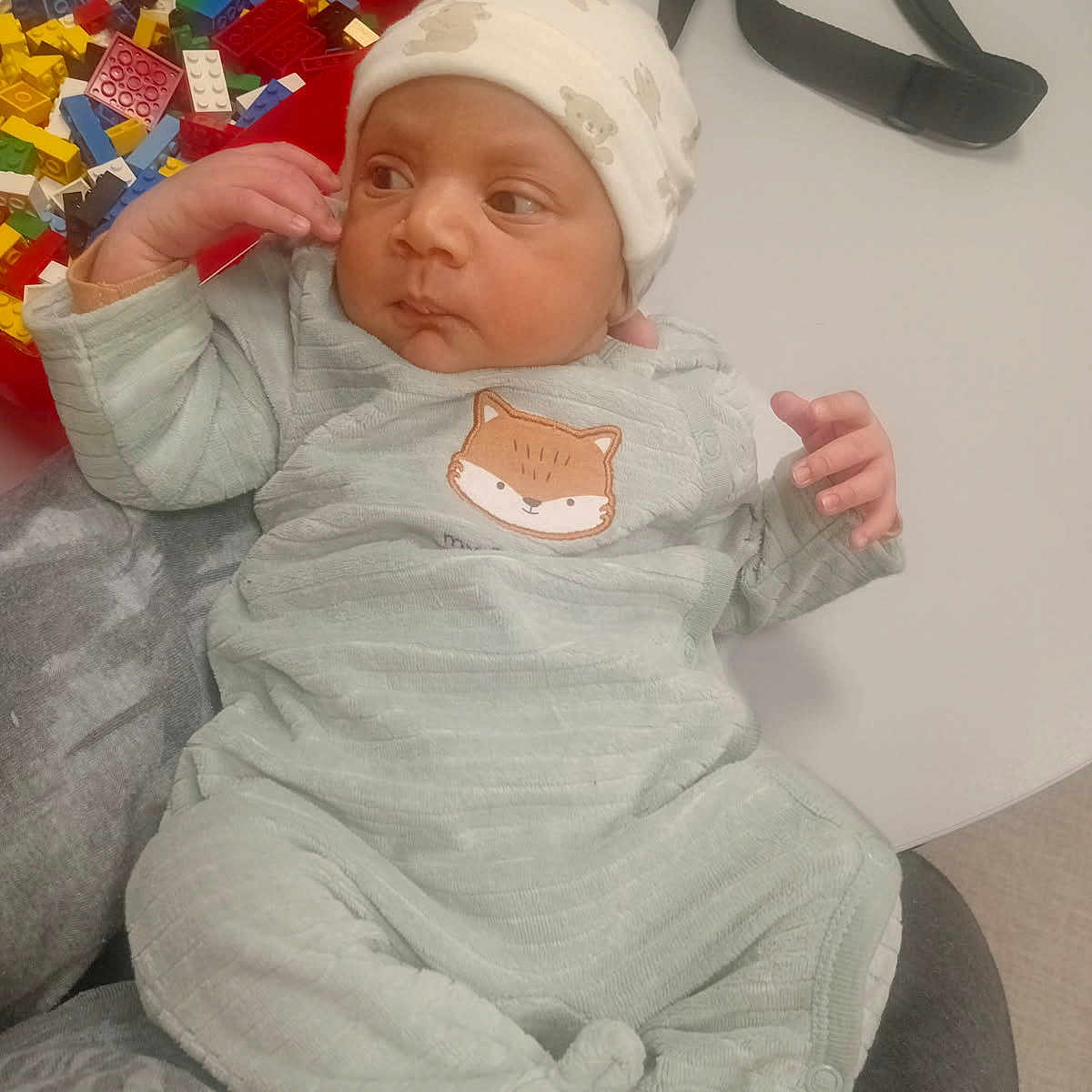 Safi a rejoint le concours — aidez-le/la à gagner de superbes lots ! accessory, baby, building_blocks, child, clothing, colorful, cute, face, hand, hat, indoor, infant, lap, onesie, person, resting, sitting, soft_fabric, table, toy