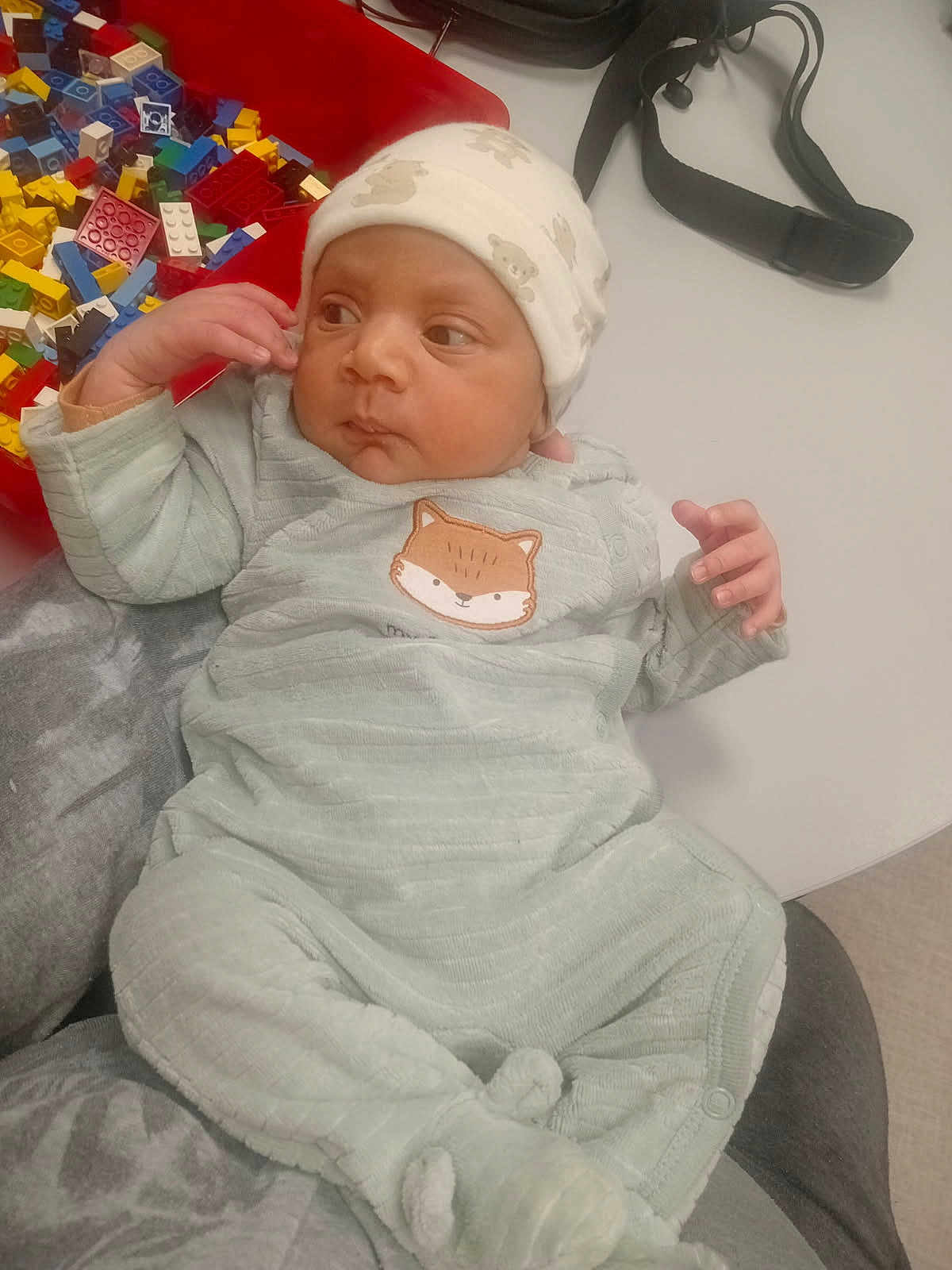 Safi a rejoint le concours — aidez-le/la à gagner de superbes lots ! baby, infant, onesie, hat, person, hand, face, table, toy, building_blocks, colorful, clothing, sitting, indoor, soft_fabric, cute, child, resting, lap, accessory