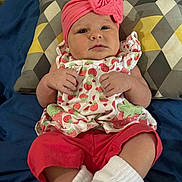 Alexis is registered to the contest to win money with this photo: baby, infant, headband, pink, bow, strawberry_pattern, clothing, pillow, blanket, red_pants, white_socks, cute, portrait, indoor, child, person, lying_down, soft_fabric, colorful, comfortable
