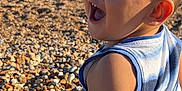 Tom is registered to the contest to win money with this photo: beach, casual_clothing, child, daytime, family, fun, happy, nature, outdoor, pebbles, person, relaxation, sea, shore, smiling, summer, sunlight, toddler, vacation, water