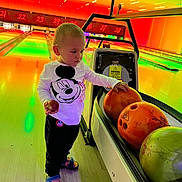 Tom joined the competition — help win amazing prizes! bowling_alley, bowling_balls, casual_clothing, child, colorful, curious, entertainment, floor, indoor, lanes, mickey_mouse, neon_lights, person, recreation, sandals, shirt, sport, standing, toddler, toy