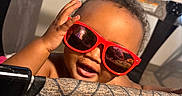 Xaniah Rose joined the competition — help win amazing prizes! baby, child, curtain, cute, expression, fabric, face, fun, hand, happy, head, indoor, pattern, person, playpen, red_sunglasses, skin, smile, sunglasses, young_child