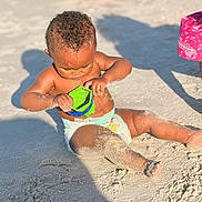 Xaniah Rose is registered to the contest to win money with this photo: toddler, child, beach, sand, toy, bucket, playing, sunlight, shadow, diaper, curly_hair, outdoor, summer, bare_chest, barefoot, sitting, skin, daytime, fun, exploring