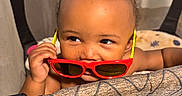 Xaniah Rose is registered to the contest to win money with this photo: baby, toddler, child, playpen, sunglasses, red_sunglasses, yellow_arms, curly_hair, face, eyes, hand, infant, indoor, peek, cute, cheeky, skin, portrait, toy, fabric