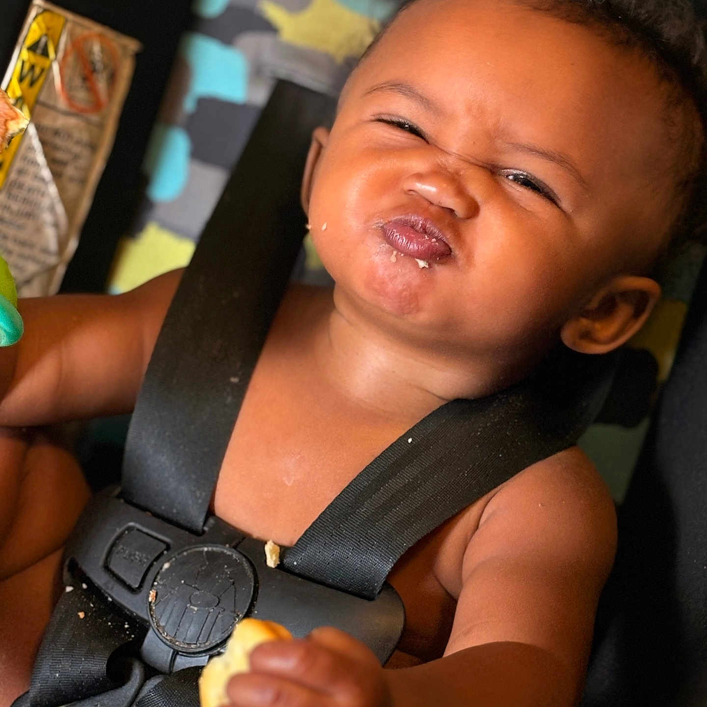 Xaniah Rose joined the competition — help win amazing prizes! baby, child, car_seat, food, crumbs, expression, face, straps, seat_belt, hand, skin, mouth, hair, indoors, closeup, colorful_background, messy, cute, infant, person