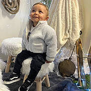 élyo a rejoint le concours — aidez-le/la à gagner de superbes lots ! black_pants, blanket, child, cozy, curious, decorations, fairy_lights, fleece_jacket, floor_rug, fluffy, happy, home, indoor, portrait, rope, smiling, sneakers, stool, toddler, wooden_stool