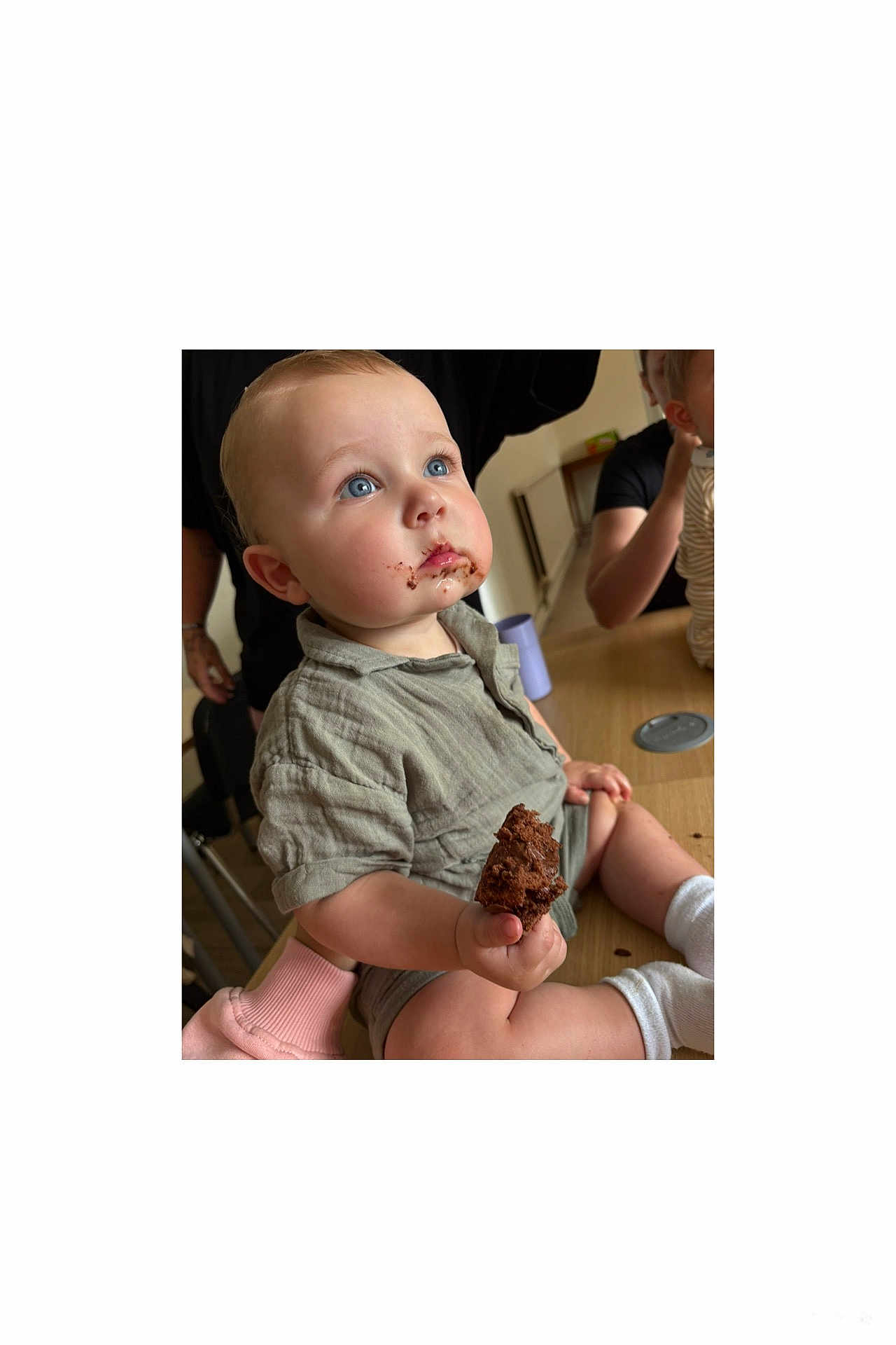 Elijah is registered to the contest to win money with this photo: baby, child, blue_eyes, chocolate, cake, food, messy, table, indoor, person, clothing, sitting, cute, face, hand, happy, snack, mouth, family, casual