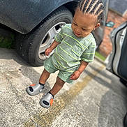 Quintrell joined the competition — help win amazing prizes! toddler, child, cornrows, green_shirt, shorts, parking_lot, car, tire, sidewalk, shoes, smile, outdoor, daylight, person, young_child, casual_clothing, earrings, concrete, vehicle, standing