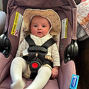 Emmy joined the competition — help win amazing prizes! baby, infant, car_seat, hat, white_clothing, safety_belt, seat_belt, face, child, cute, indoors, fabric, blanket, warning_label, pink, mauve, person, seat, sitting, portrait