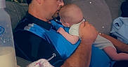 Hunter is registered to the contest to win money with this photo: affection, baby, blanket, bottle, camouflage, casual, comfort, couch, glasses, heart, holding, indoor, infant, love, man, parent, portrait, relaxation, seated, shirt