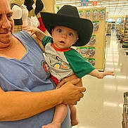 Hunter joined the competition — help win amazing prizes! adult, baby, being_held, blue_dress, child, clothing, cowboy_hat, face, family, fluorescent_lighting, green_shirt, grocery_store, indoors, portrait, retail, shopping_cart, sitting, store_aisle, supermarket, wide_eyed