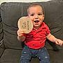 baby, child, infant, smiling, couch, red_shirt, blue_pants, celestial_prints, wooden_sign, ten_months, happy, sitting, indoors, person, face, hand, furniture, home, cute, portrait