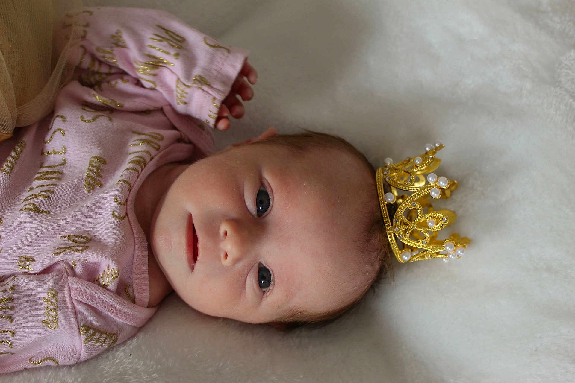 Aayla is registered to the contest to win money with this photo: adorable, baby, blanket, child, crown, cute, face, gold, head, infant, lying_down, newborn, onesie, pearl, pink_clothing, portrait, resting, royalty, soft_texture, young