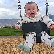Aayla joined the competition — help win amazing prizes! baby, child, swing, playground, outdoor, smiling, happy, clothing, jacket, mountains, sky, clouds, woodchips, seat, chains, bench, grass, person, feet, sock