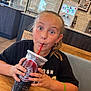 Aliyah is registered to the contest to win money with this photo: child, soda, cup, straw, table, restaurant, fast_food, drink, black_shirt, bracelet, indoor, face, person, happy, seated, wooden_table, beverage, casual, expression, hair_tied