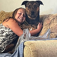 Aliyah is registered to the contest to win money with this photo: child, girl, dog, hug, couch, living_room, smile, pet, friendship, fabric, plastic_bag, black_and_white_dress, furniture, indoor, home, comfort, happy, animal, canine, portrait