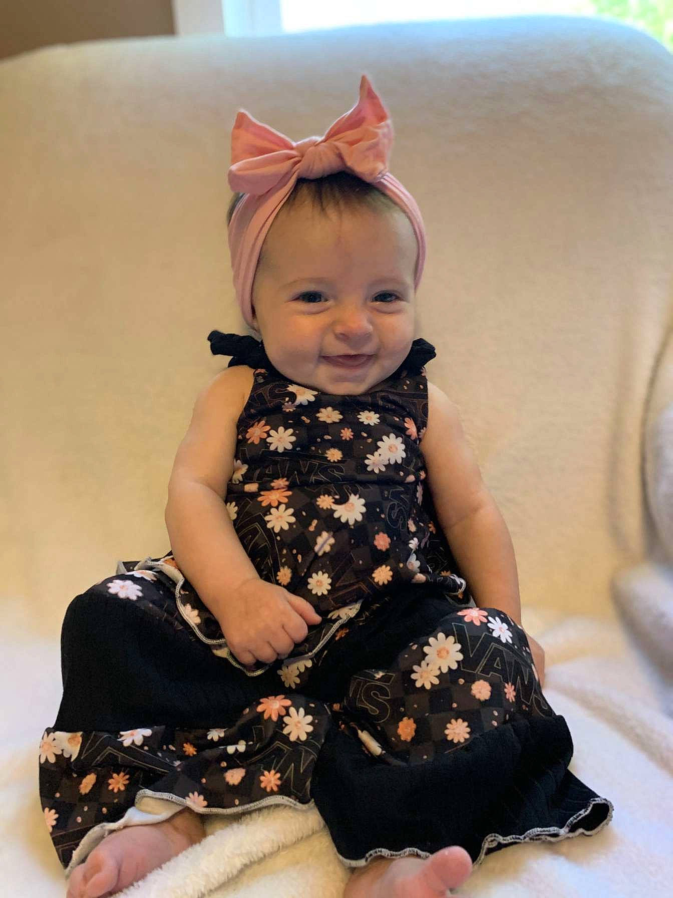 Nyla is registered to the contest to win money with this photo: baby, baby_toddler_clothing, child, day_dress, dress, fashion_accessory, hair_accessory, happy, headpiece, jewellery, joy, one_piece_garment, pattern, person, pink, sitting, skin, sleeve, smile, tie