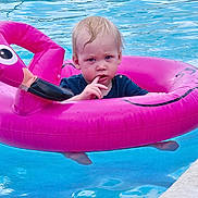 Nash is registered to the contest to win money with this photo: toddler, child, pool, water, inflatable, flamingo, float, swimming, summer, outdoor, wet_hair, blue_shirt, reflection, thinking, cute, baby, fun, leisure, vacation, play