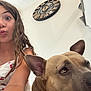 child, girl, dog, pet, indoor, clock, wall, white_wall, cute, playful, selfie, face, animal, brown_dog, young, hair, smile, curly_hair, casual_clothing, portrait