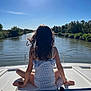 child, girl, boat, river, water, sunlight, sky, nature, trees, outdoor, summer, back_view, relaxation, calm, scenery, travel, vacation, daytime, watercraft, serene