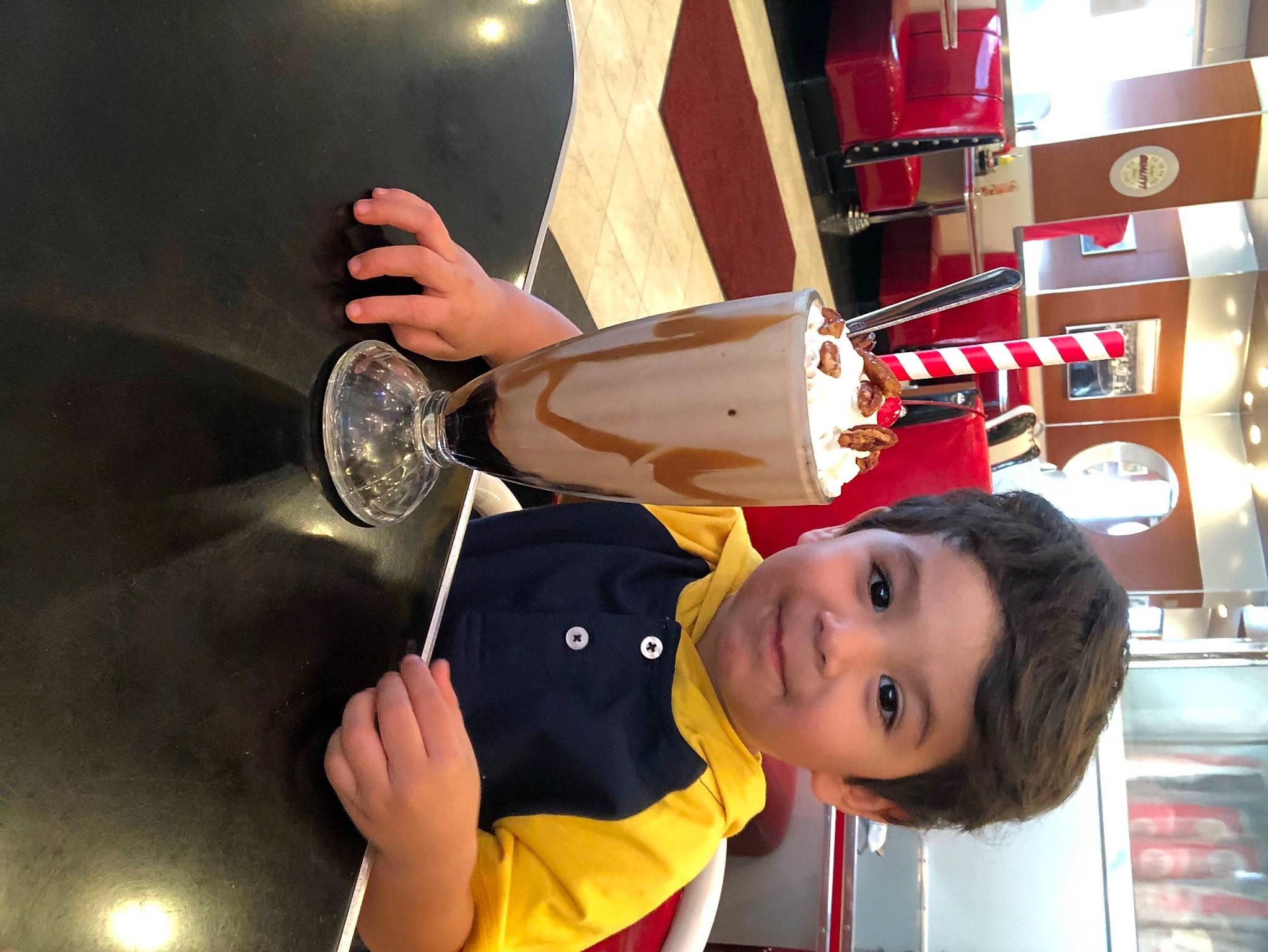 Damian is registered to the contest to win money with this photo: carmine, child, elbow, finger, fun, gesture, happy, hat, human_leg, joy, knee, nail, person, room, smile, tableware, thigh, thumb, tire, toddler