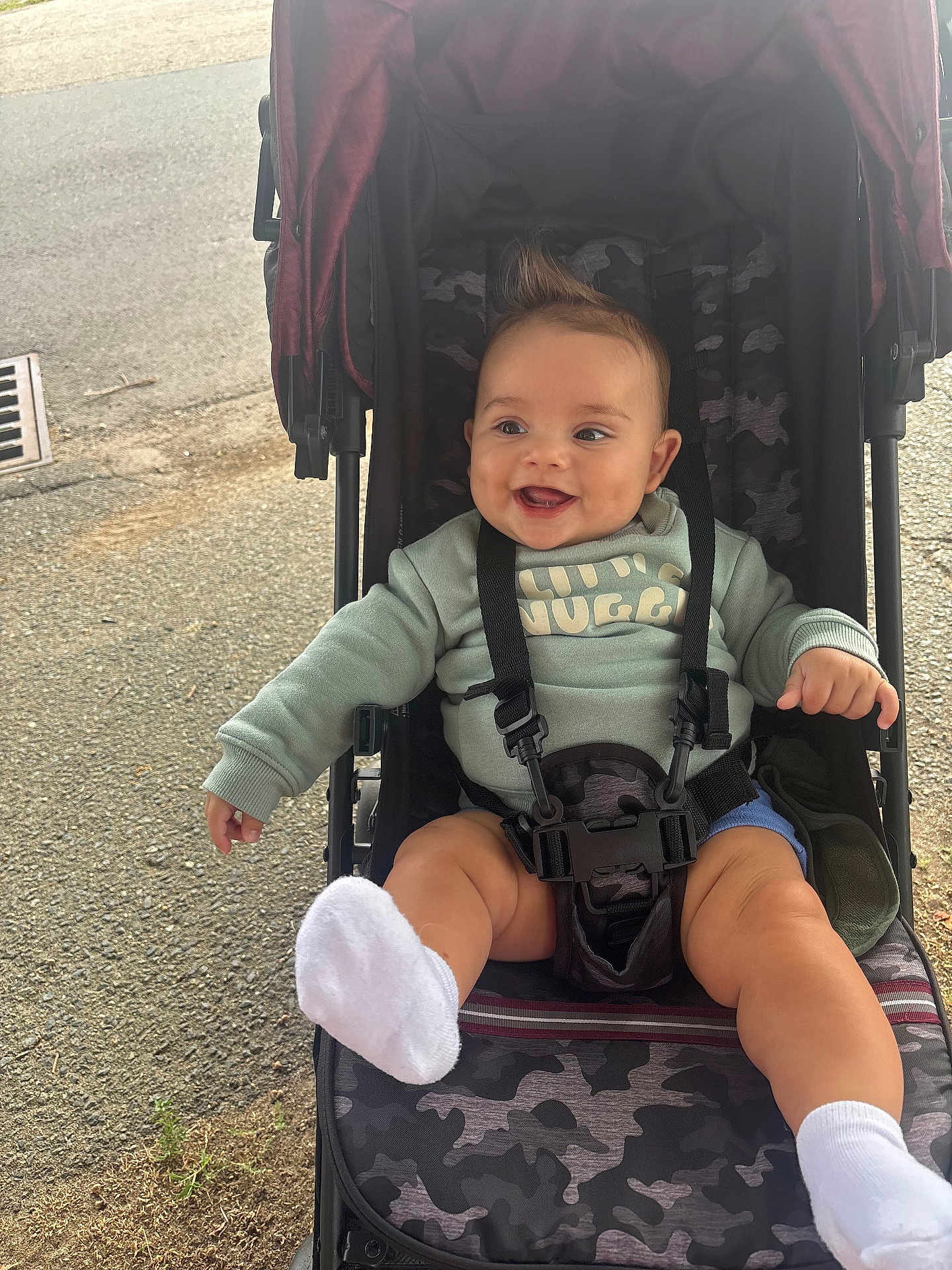 Myles joined the competition — help win amazing prizes! baby, child, stroller, smiling, happy, sock, camo_pattern, clothing, outdoor, seatbelt, footwear, person, infant, playful, mohawk, sitting, cute, expression, baby_clothes, daylight
