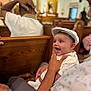 baby, child, infant, smiling, happy, person, hat, white_clothing, indoor, church, wooden_pews, adult_hand, portrait, seated, people, family, celebration, cute, bright_eyes, holding