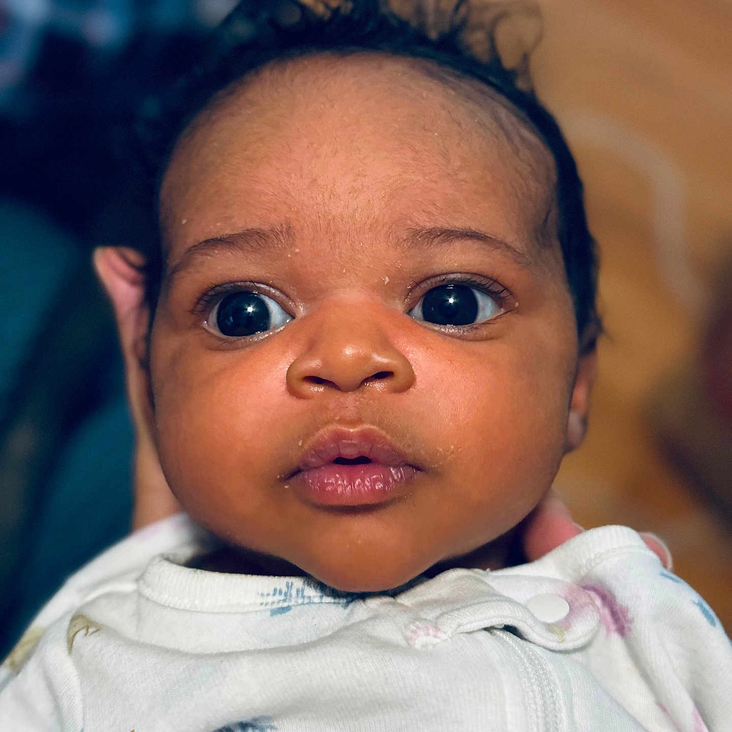 Kenza is registered to the contest to win money with this photo: baby, child, closeup, clothing, curious, cute, expression, face, focus, hand, head, indoor, infant, newborn, onesie, person, portrait, skin, soft_lighting, wide_eyes