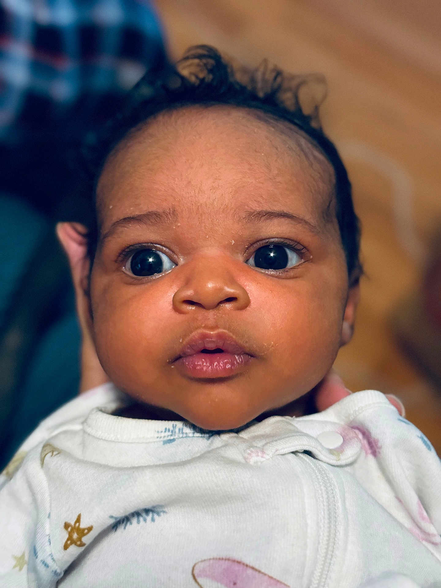 Kenza is registered to the contest to win money with this photo: baby, infant, face, closeup, curious, wide_eyes, expression, clothing, onesie, soft_lighting, portrait, cute, child, newborn, person, skin, head, hand, indoor, focus