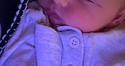 Deacon is registered to the contest to win money with this photo: baby, sleeping, infant, portrait, close_up, face, eyes_closed, peaceful, indoor, clothing, onesie, buttons, blanket, fabric, purple_lighting, cozy, resting, head, cheeks, photography