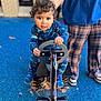 child, toddler, curly_hair, playground, spring_rider, blue_pavement, pajamas, person, adult, plaid_pants, handlebar, outdoor, leaves, toy, feet, expression, face, holding, casual_clothing, daylight