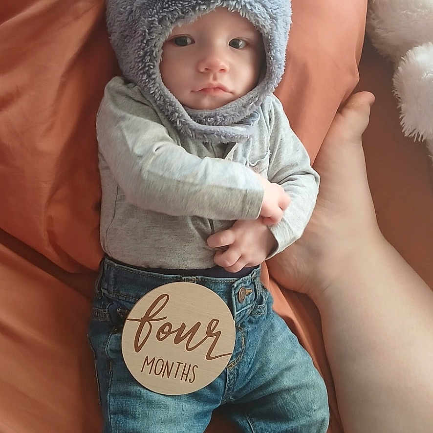Dennis joined the competition — help win amazing prizes! baby, infant, child, hat, bear_hat, striped_socks, jeans, wooden_sign, four_months, blanket, bed, hand, cute, lying_down, indoor, portrait, cozy, soft_toys, casual_clothing, person