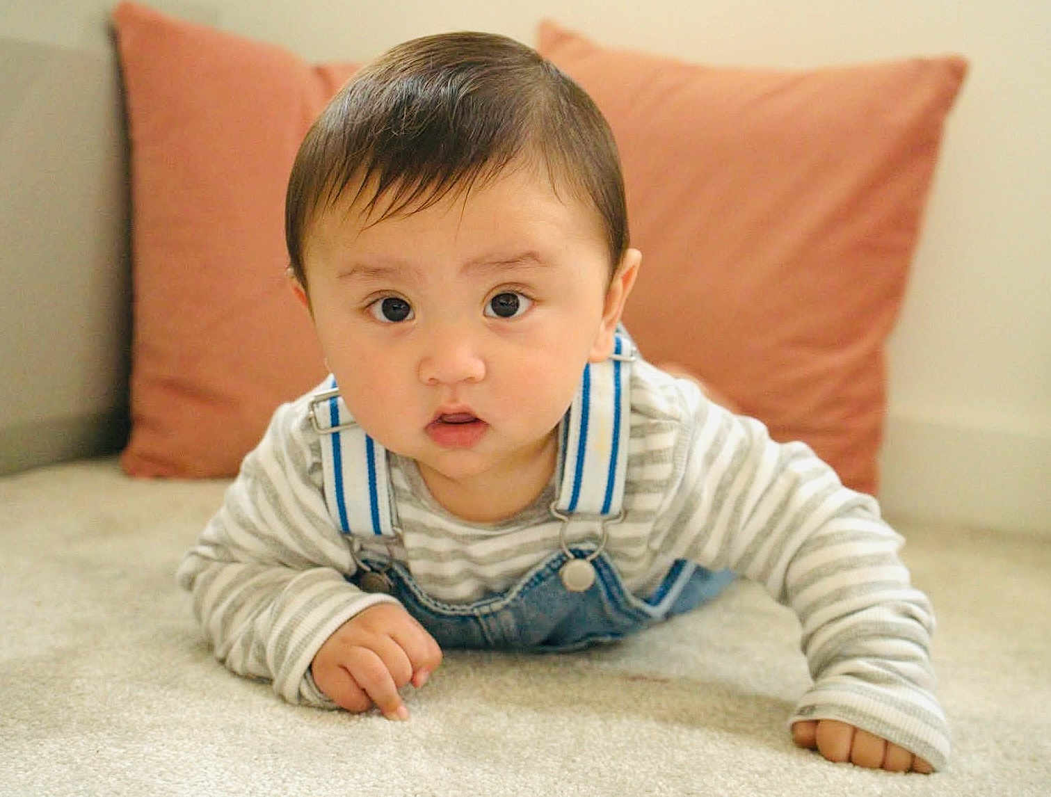 Suryan joined the competition — help win amazing prizes! baby, child, infant, face, eyes, clothing, denim, overalls, striped_shirt, carpet, floor, cushion, indoor, cute, portrait, young, person, skin, hand, expression