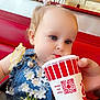 toddler, child, drinking, cup, fast_food, restaurant, booth, red_seat, blue_dress, flowers, hair_bows, hand, table, poster, burger, window, light, interior, person, casual
