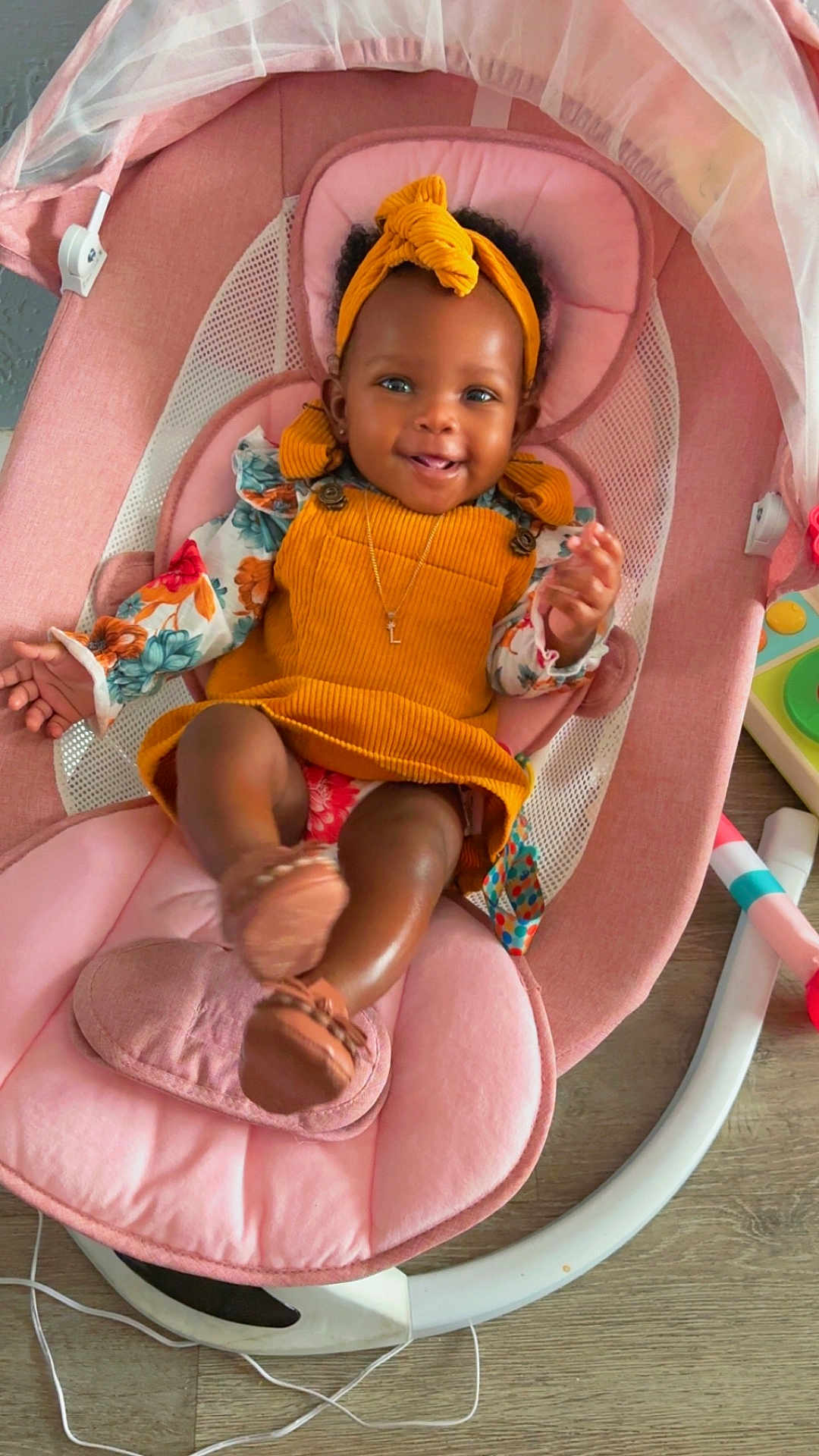 Lay Ani joined the competition — help win amazing prizes! baby, infant, smiling, child, headband, yellow_dress, pink_rocker, cushion, toy, wooden_floor, happy, indoor, person, cute, footwear, sitting, portrait, childcare, colorful, relaxed