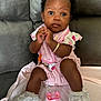 Lay Ani is registered to the contest to win money with this photo: baby, infant, child, pink_outfit, white_shoes, lace, bracelet, pacifier, blanket, couch, indoors, clothing, cute, face, hands, sitting, expression, portrait, person, accessory