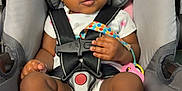 Lay Ani is registered to the contest to win money with this photo: baby, infant, car_seat, headband, clothing, socks, pacifier, black_hair, straps, sitting, pink, gray, child, cute, indoors, closeup, face, hand, toy, secure