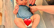 Hudson is registered to the contest to win money with this photo: adult_hands, baby, bath, bathroom, bathtub, blue_onesie, child, cleaning, cute, digital_thermometer, heart_emoji, infant, person, plastic_tub, sitting, skin, smiling, towel, water, water_temperature