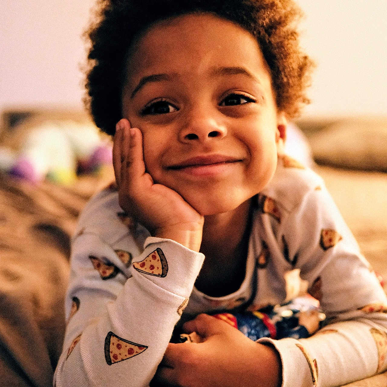 Nils participe au concours pour gagner de l'argent avec cette photo : bed, casual, child, cozy, curly_hair, cute, hand_on_face, happy, home, indoor, pajamas, person, pizza_pattern, portrait, relaxed, resting, sleepwear, smiling, warm_lighting, young
