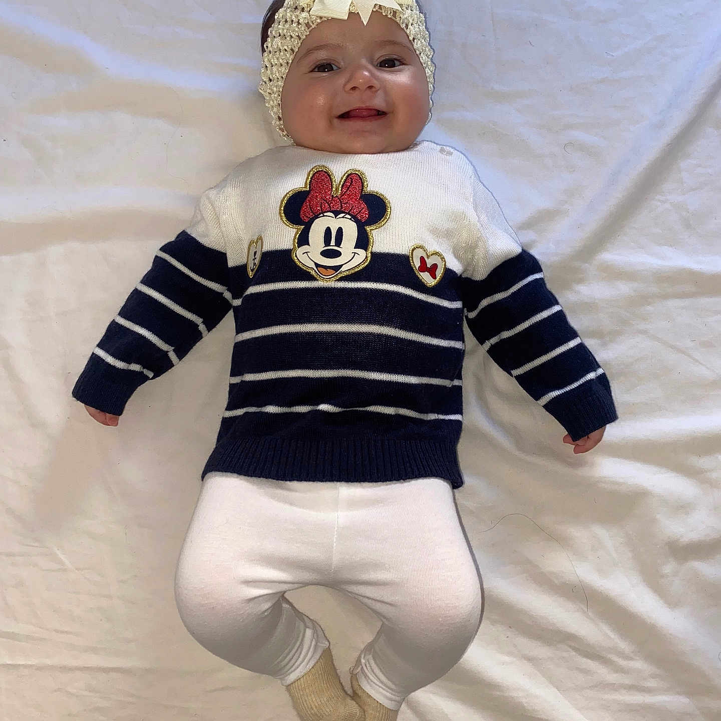 Cataleya participe au concours pour gagner de l'argent avec cette photo : baby, smiling, lying_down, headband, bow, sweater, minnie_mouse, striped_clothing, white_leggings, socks, infant, cute, happy, child, portrait, indoors, fabric, clothing, person, young_child