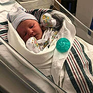 Makayla joined the competition — help win amazing prizes! baby, newborn, infant, hospital, bassinet, blanket, swaddle, hat, pacifier, crib, mittens, striped_pattern, medical_equipment, nursery, bed, portrait, face, awake, hospital_blanket, cot