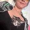 kitten, cat, woman, person, portrait, selfie, glasses, eyewear, clothing, black_shirt, plaid, jacket, necklace, indoor, closeup, furry, fluffy, gray_cat, pet, cuddling