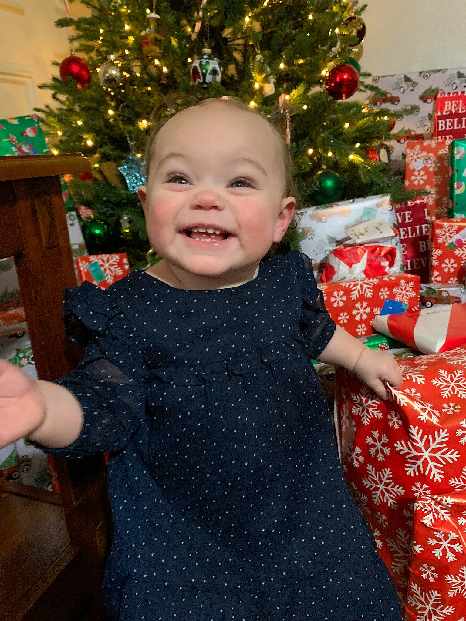 Eden is registered to the contest to win money with this photo: baby, baby_toddler_clothing, child, christmas, christmas_decoration, christmas_ornament, christmas_tree, dress, eye, face, facial_expression, happy, head, holiday, holiday_ornament, joy, person, skin, smile, standing