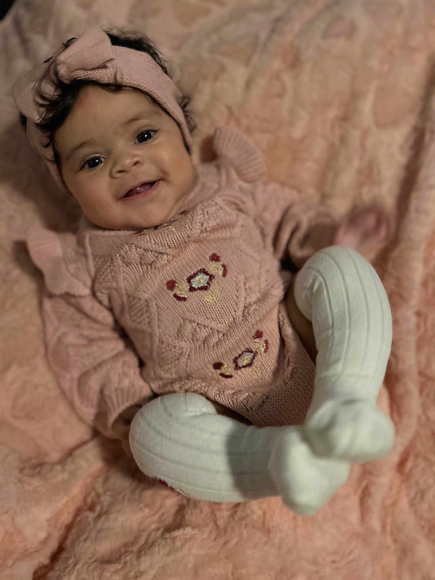 Emmery is registered to the contest to win money with this photo: baby, smiling, infant, knitted_clothing, headband, pink, blanket, soft_texture, cute, happy, portrait, indoors, cozy, baby_girl, socks, toddler, face, person, child, apparel