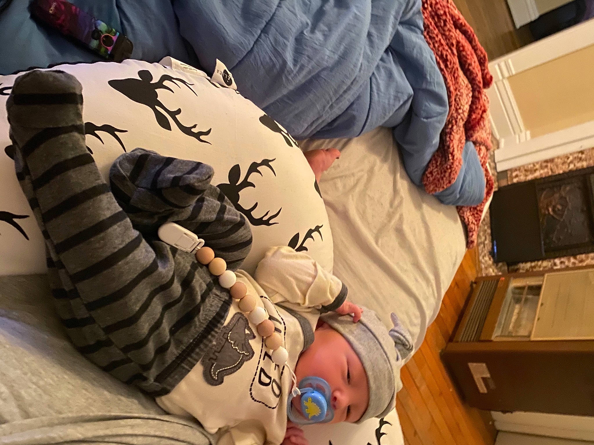 Benji is registered to the contest to win money with this photo: abdomen, baby, carmine, chest, comfort, elbow, flesh, flooring, headwear, human_leg, knee, linens, pattern, person, sitting, sleeve, t_shirt, tattoo, thigh, toddler