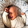 baby, smiling, infant, sleeping, cozy, blanket, cushion, toy, cute, child, soft_lighting, indoors, clothing, peaceful, happy, newborn, portrait, resting, comfort, warm
