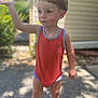 Anthony is registered to the contest to win money with this photo: barefoot, blurry_background, casual_clothing, child, curious, expression, greenery, nature, outdoor, playful, portrait, red_onesie, short_hair, sidewalk, standing, summer, sunlight, sunny_day, toddler, young_child