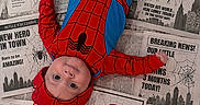 Logan is registered to the contest to win money with this photo: baby, infant, spiderman_costume, costume, newspaper, 3_months, superhero, child, portrait, cute, lying_down, celebration, face, headwear, red, blue, cartoon, spider, web, milestone