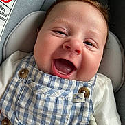 Logan joined the competition — help win amazing prizes! baby, smiling, happy, child, infant, face, overalls, blue_and_white, checkered, car_seat, button, clothing, cute, person, closeup, skin, head, expression, joy, indoors